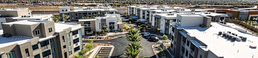 a group of new apartment buildings in a parking lot with mountains in the background at BASE APARTMENT HOMES, LAS VEGAS, Nevada