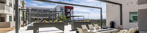 A patio with chairs and a table is surrounded by buildings.