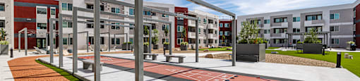 A playground with a slide and a climbing frame in front of apartment buildings.