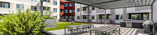 A patio with tables and chairs is shaded by a roof.