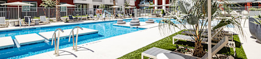 A pool surrounded by lounge chairs and umbrellas.