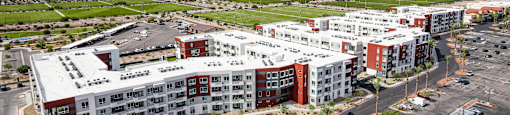 A large apartment complex with a parking lot in front.