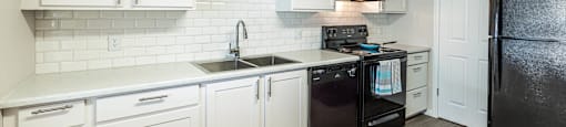 a kitchen with white cabinets and black appliances at Mountain Run Apartments, Orem, Utah