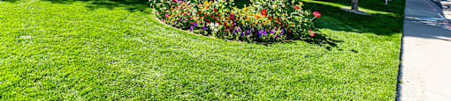 a view of the front of a building with a lawn and flowers at Mountain Run Apartments, Orem, Utah