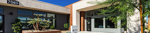 the front of a building with a sidewalk and landscaping