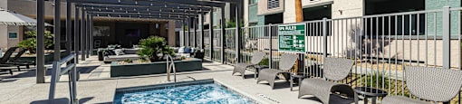 a swimming pool in front of a building with palm trees