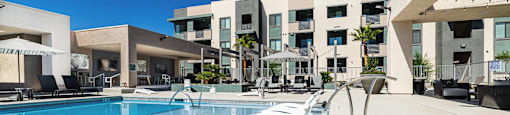 a large pool with lounge chairs in front of a building