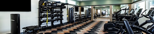 a gym with cardio machines and weights on the floor