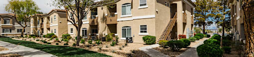 exterior view of multiple apartment buildings with sidewalks and grass and trees at THE CLUBS AT RHODES RANCH APARTMENT HOMES, Nevada, 89148