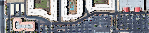 A large parking lot is surrounded by buildings and a soccer field.