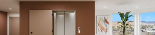 A room with a brown door and a plant on a white pedestal.