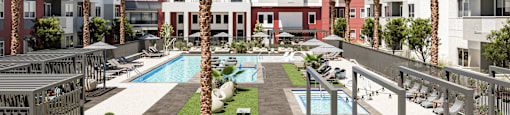 A pool surrounded by palm trees and lounge chairs.