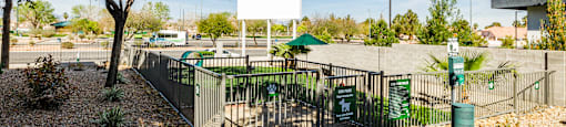 A white sign is on a gate in front of a green bush.
