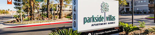 A sign for Parkside Villas Apartment Homes is in front of a palm tree.