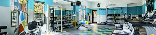 A gym with a variety of equipment including treadmills, weights, and a fan.