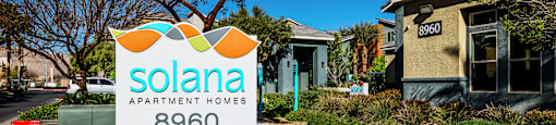 A sign for Solana Apartment Homes in front of a building.