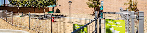 A dog park sign is displayed on a fence.