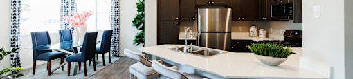 A modern kitchen with a bar stool and a dining table.