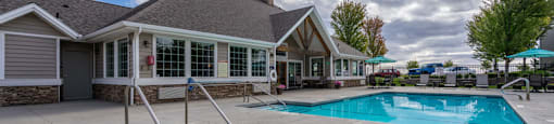 A small pool with a slide in front of a house.