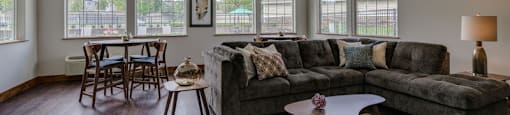 A living room with a grey couch, wooden chairs, and a coffee table.