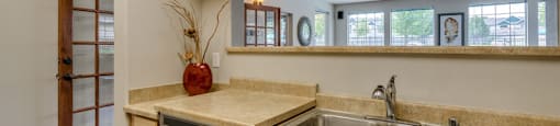 A kitchen with wooden cabinets and a stainless steel dishwasher and sink.