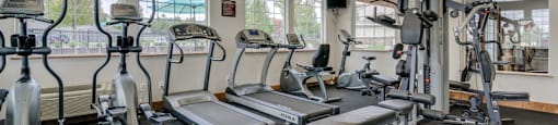 Dog-Friendly Apartments In Spokane, WA - Deer Creek - Fitness Center With Cardio Equipment, Workout Benches, Strength Training Machines, and Large Windows.