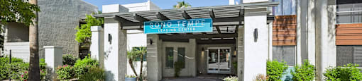 The image shows a building entrance with a sign that reads "SOMETHING" above the door.