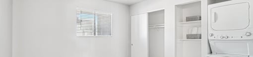 A white fridge in a room with white walls and wooden flooring.