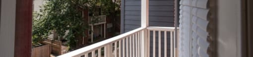 a porch with a white railing and a tree in the background