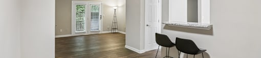 A room with a wooden floor and two black chairs.
