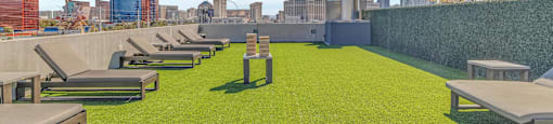 A rooftop garden with green grass and wooden benches.