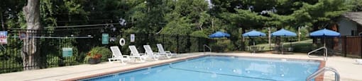 a large swimming pool with lounge chairs and umbrellas