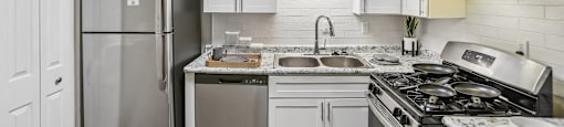 A kitchen with a refrigerator, stove, and sink.