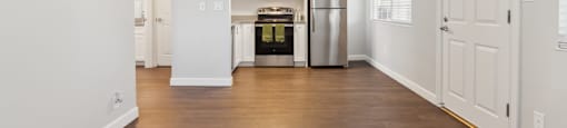 A kitchen with white cabinets and a wooden floor.