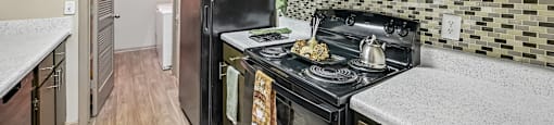A kitchen with a black stove top oven and a black microwave above it.