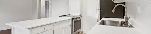 A white kitchen with a sink and stove.