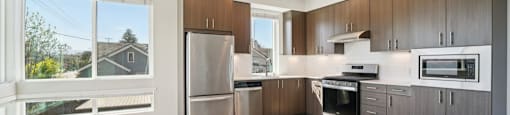 A modern kitchen with wooden floors and stainless steel appliances.