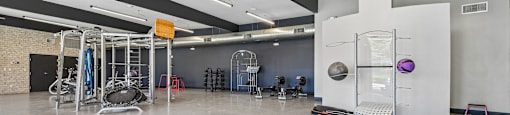 A gym with a variety of equipment including a tire flipper, a bench, and a rowing machine.