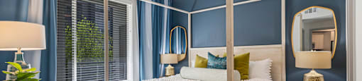 A bedroom with a four poster bed and a window with blue curtains.
