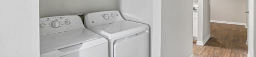 Two white front load washing machines in a laundry room.