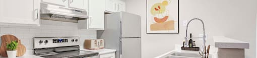 Glendale, AZ, Apartments For Rent - Spectra West - Kitchen With Wood-Look Flooring, All-Electric Stainless Steel Kitchen Appliances, Flat-Top Cooking Range, White Cabinets, And Granite Countertops.
