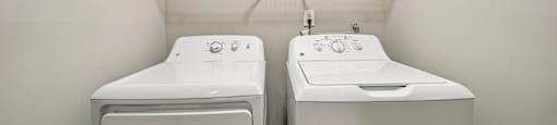 Two white washing machines in a laundry room.