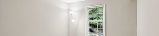 A room with a carpeted floor and a window with blinds.