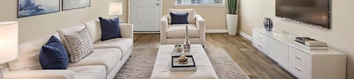 A living room with a white couch, a coffee table, and a television.