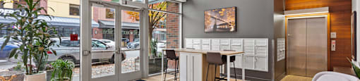 A modern office lobby with a chair, desk, and potted plant.