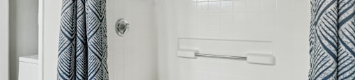 A white bathtub with a shower curtain on the side.