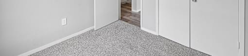 A white room with a carpeted floor and a doorway leading to another room.