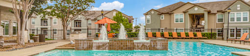 San Antonio, TX Apartments - Club at Stone Oak - Resort-Style Pool with Water Feature, Lounge Chairs, Umbrellas, and Beautiful Landscaping