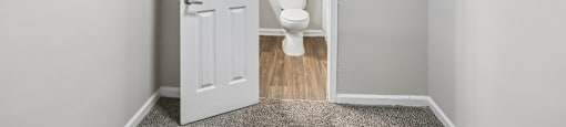 A white door is open to a bathroom with a toilet.