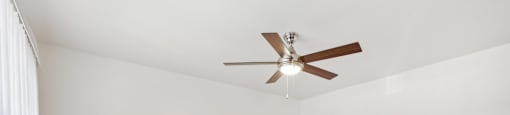 A room with a ceiling fan and carpeted floor.
